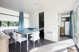 图尔恩Donaupark Camping Tulln的厨房以及带玻璃桌和白色椅子的用餐室。