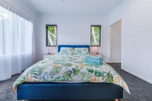 埃尔利海滩Hillside Haven - Airlie Beach的一间卧室设有蓝色的床和2个窗户。
