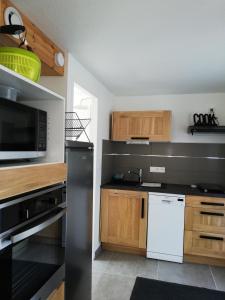 克拉斯卡诺特Les vacances aux Pouldu的厨房配有木制橱柜和黑微波炉