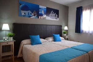 阿瓜杜尔塞Hostales Juan de Austria I & II的一间卧室配有一张带蓝色枕头的大床