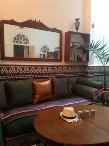 丹吉尔达纳科拉莱西利亚酒店的客厅配有一张沙发,桌子上挂着一顶帽子