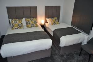 伦敦伦敦曼诺豪斯酒店的两间位于酒店客房的床,中间有灯