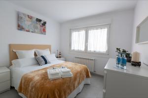 庞特维德拉Alameda Home Pontevedra的白色卧室,配有带毛巾的床