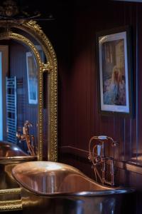 奥尔克汉姆The Marquis of Granby的一间带金色浴缸和镜子的浴室