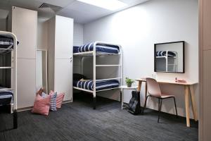 珀斯Spinners Hostel的宿舍间设有双层床、书桌和桌子。