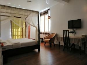 努沃勒埃利耶Melford Nuwaraeliya的一间卧室配有一张床、一张桌子和一台电视