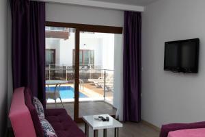 图尔古特雷斯Siesta Garden Apart Hotel的客厅配有紫色沙发和电视