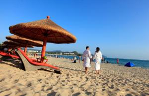三亚三亚柏瑞精品海景酒店的两人在海滩上用遮阳伞散步