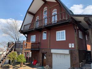 札幌Sapporo Luxury Log House 5Brm max 18ppl 4 free parking的一座大型红色房子,设有甲板和车库