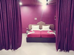 KondottiHotel Nuhman的一间卧室配有一张紫色墙壁和窗帘的床