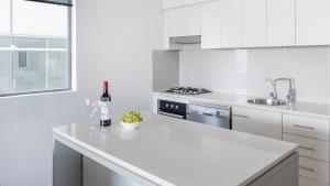 布里斯班Oaks Brisbane on Margaret Suites的白色的厨房,在柜台上提供一瓶葡萄酒