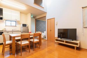 别府Ecol Beppu的厨房以及带桌子和电视的用餐室。