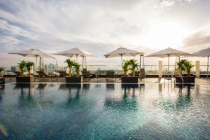 迪拜The Canvas Dubai - MGallery Hotel Collection的大楼内带遮阳伞和椅子的游泳池