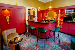 伍珀塔尔公园别墅酒店的一间红色的酒吧,里面摆放着绿色的椅子