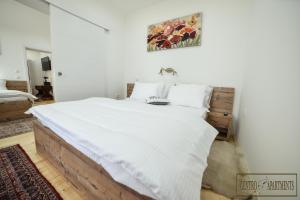 斯雷姆斯卡米特罗维察Centro Apartments的一间卧室配有一张带白色床单的大床