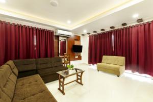 科钦Burooj Hotel的客厅配有红色窗帘、沙发和椅子