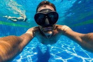San Juan del Cesar萨拉约酒店的男人在游泳池游泳,身着一双眼花