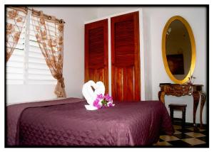 CaibariénHostal "Villa Blanca"的一间卧室配有一张带紫色床罩和鲜花的床