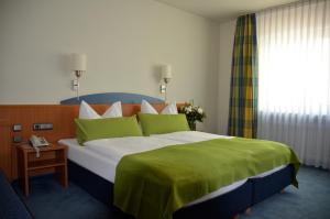 美因河畔法兰克福舒尔巴赫霍夫兰德酒店的一间卧室配有一张带绿毯的大床