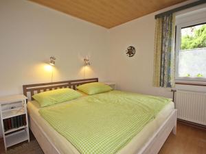 GlanzApartment Annemarie by Interhome的一间卧室配有一张带绿色床单的床和一扇窗户。