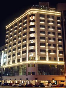 斗六市致丽伯爵酒店的一座有照明的建筑,前面有汽车停放
