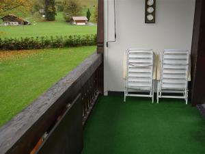 格施塔德Apartment Oberland Nr- 29 by Interhome的两把椅子坐在带绿草的门廊上