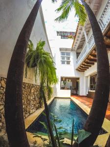 卡塔赫纳Hotel Casa la Tablada的一座建筑前的游泳池,两棵棕榈树