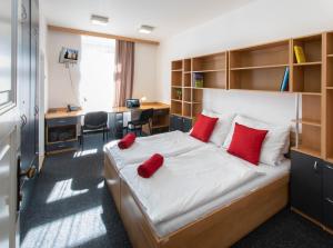 布拉格马萨里克大学酒店的一间卧室配有一张带红色枕头的床