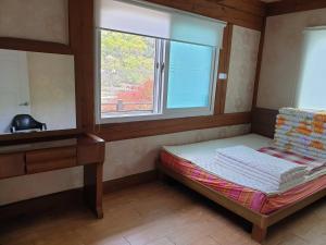 统营市Tongyeong Yehyang Pension的窗户客房内的小床