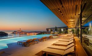 罗维尼Grand Park Hotel Rovinj by Maistra Collection的酒店设有带躺椅和桌子的游泳池。