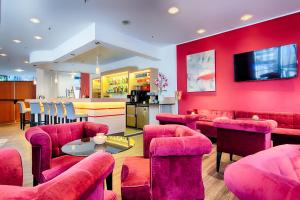 波鸿ACHAT Hotel Bochum Dortmund的餐厅设有粉红色的椅子、桌子和柜台