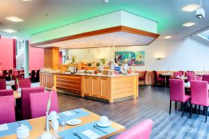 波鸿ACHAT Hotel Bochum Dortmund的一间设有粉红色桌椅的餐厅以及一间自助餐