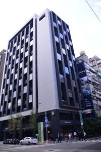 台北晴美公寓酒店的一条黑色和白色的大建筑,位于城市街道上