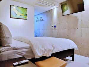 西归浦市Hotel Stay Interview Jeju的卧室配有一张床,墙上配有电视。
