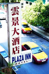 诗巫Plaza Inn的2辆汽车停在停车场,带有比萨饼店标志
