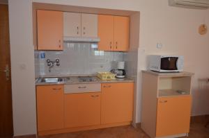 木洛希尼Apartments Anci的一个带橙色橱柜和微波炉的厨房