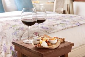 塞尔丘克VINIFERA VINEYARDS HOTEL的两杯葡萄酒和小吃放在床边的桌子上