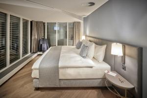 图恩Hotel Seepark Thun的一间卧室配有一张大床、一张桌子和一盏灯。