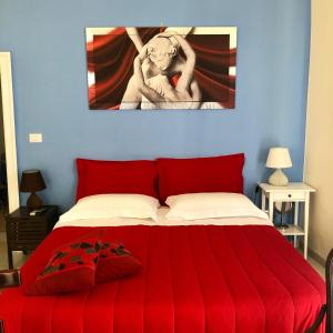 焦维纳佐Il Da Vinci casa vacanze的卧室配有红色的床,墙上挂有绘画作品