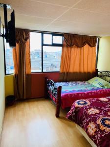 拉塔昆加Hostal Rosita Latacunga的一间卧室设有两张床和大窗户
