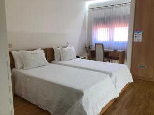 马亚机场酒店的卧室配有一张带白色床单的大床和窗户。