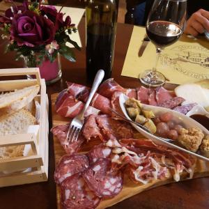 皮恩扎卡萨尔皮亚诺农庄酒店的一张桌子,上面放着一盘 ⁇ 制的肉和一杯葡萄酒