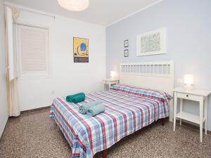 滨海圣波尔Apartment Sant Pol by Interhome的白色卧室,配有一张带格子毯子的床