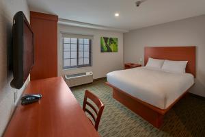 蒙特雷Extended Suites Monterrey Aeropuerto的配有一张床和一张书桌的酒店客房