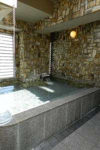 松山松山入住酒店的石墙客房,位于一栋建筑中,设有热水浴池