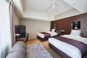 静冈HOTEL MYSTAYS Shimizu的一间酒店客房,设有两张床和电视