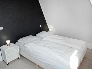 诺德克豪特Holiday Home de Witte Raaf-3 by Interhome的一张带白色床单的床和两盏灯