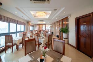 河内Hanoi Larosa Hotel的餐厅设有桌椅和大窗户。