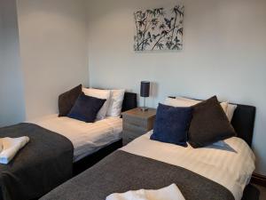 特尔福德Avon House的一间卧室配有两张带蓝色枕头的床