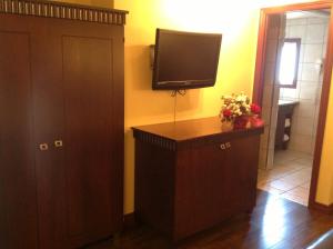 魁北克市西塔德勒酒店的一间配有电视的房间和一个带鲜花的橱柜